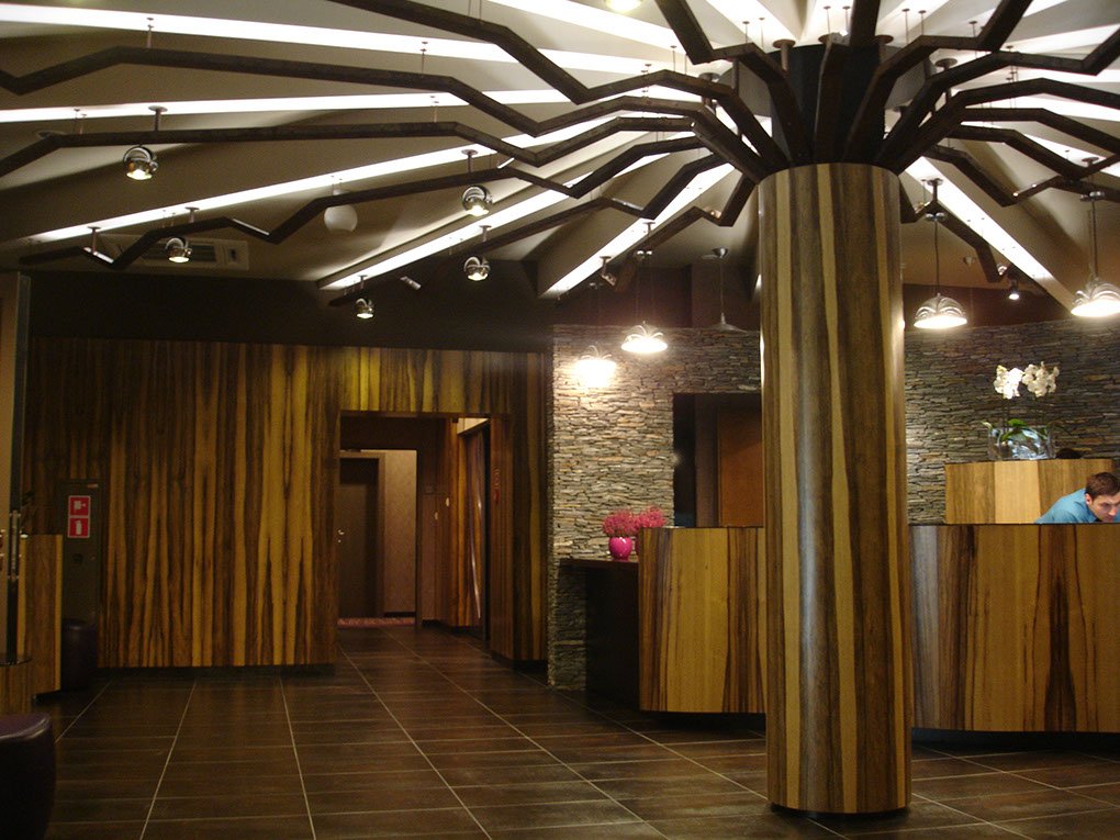 Nietypowe oświetlenie w hotelowej recepcji, kolumna ze stelażem imitującym rozłożony parasol