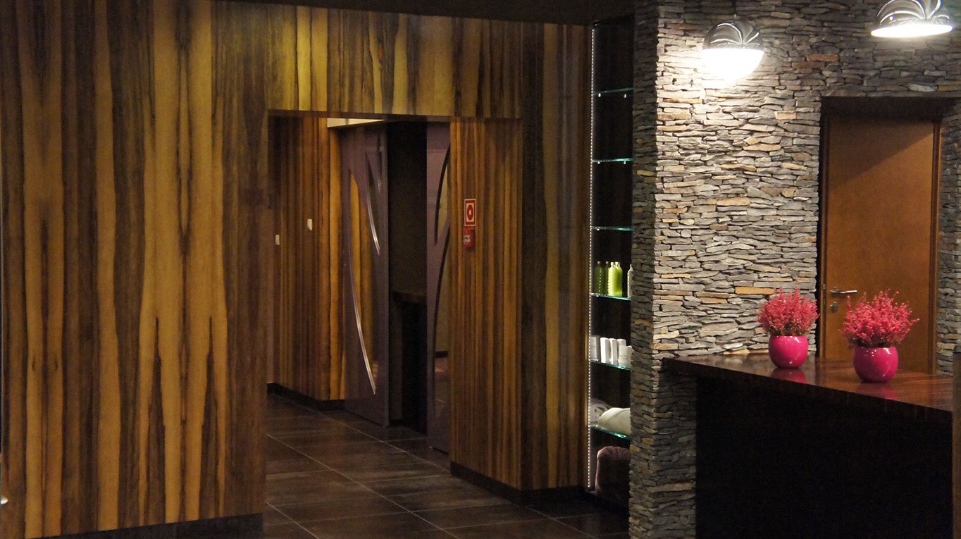 Recepcja w hotelu, przejście na korytarz a w nim drzwi z lustrem ażurowym do szatni