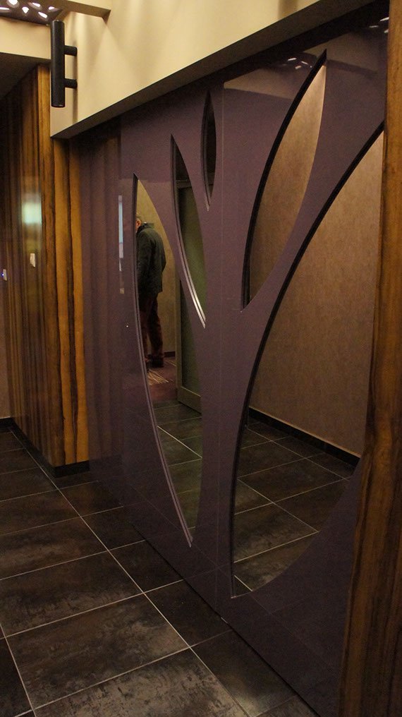 Rozsuwane drzwi do szatni w hotelu zamknięte, ażurowe lustra ułożone w kształcie liści