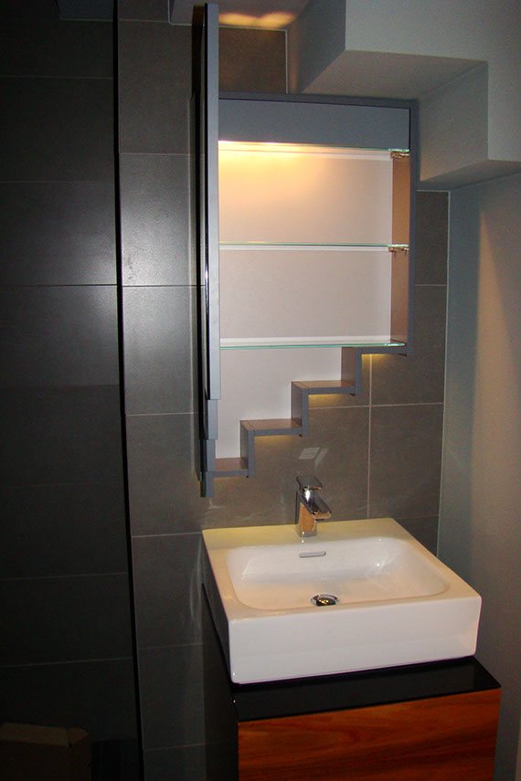 Zbliżenie na otwarte lustro w łazience pod schodami, szklane półki wewnątrz