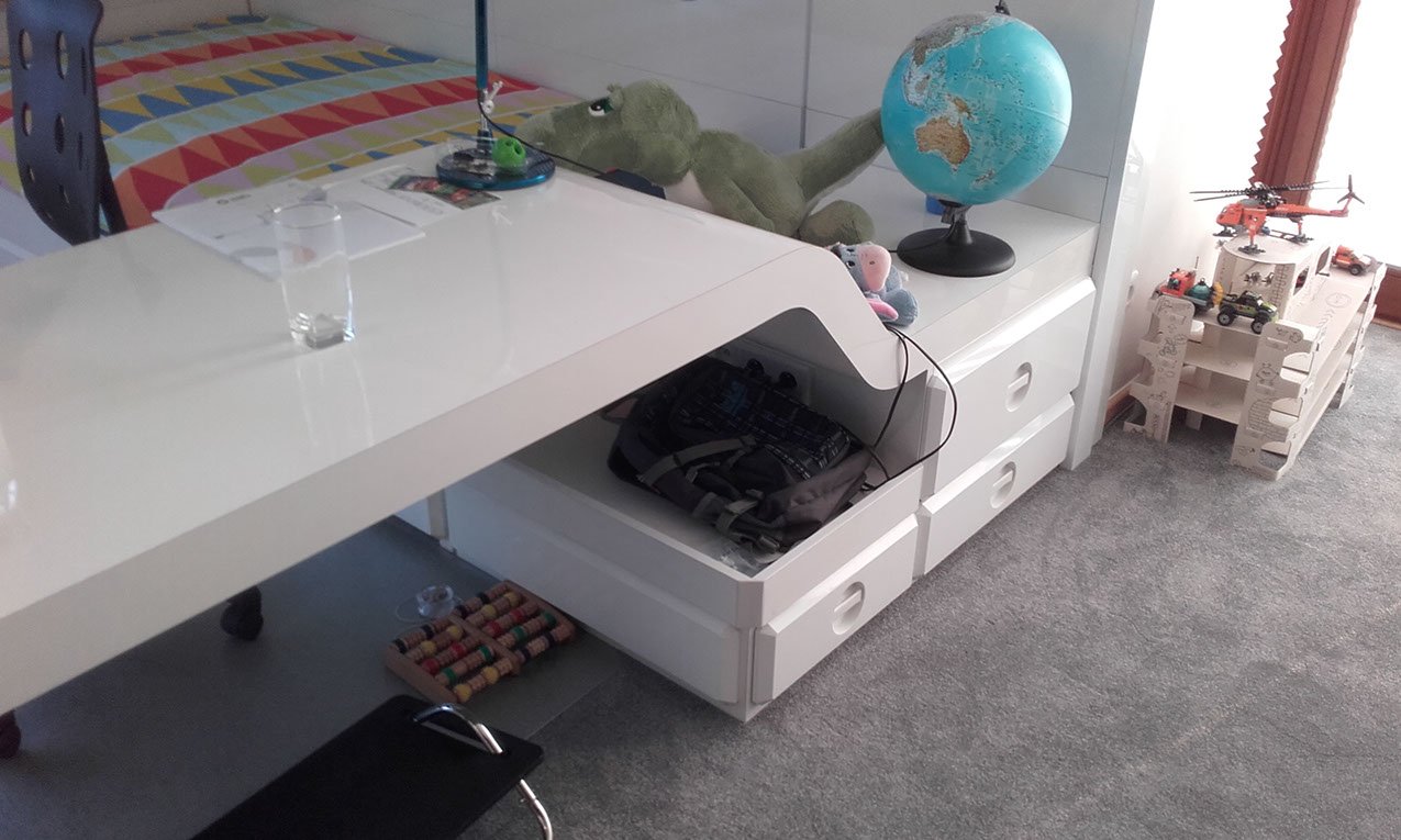 Blat biurka w pokoju stylizowanym na statek kosmiczny, wyfrezowany w łagodne łuki popadające na szafkę. Meble na wymiar